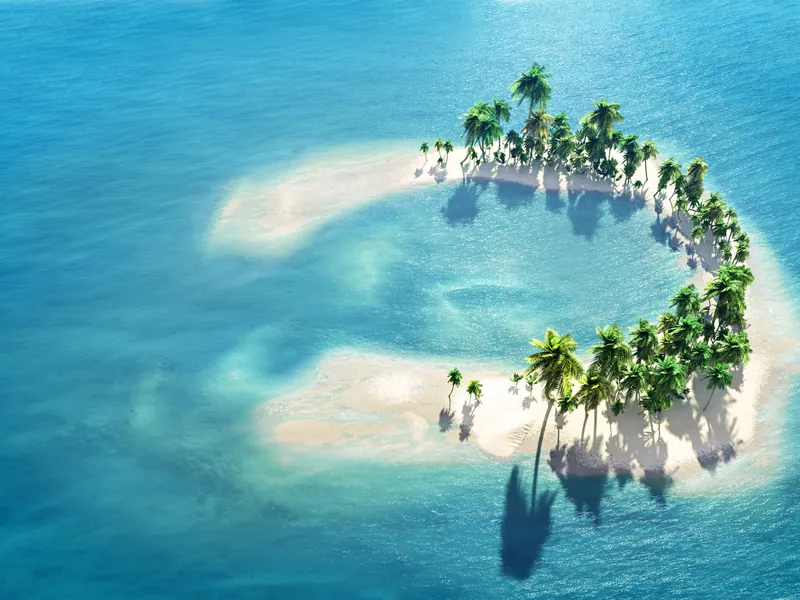 A sandbank with a few palms surrounded by shallow turquoise water