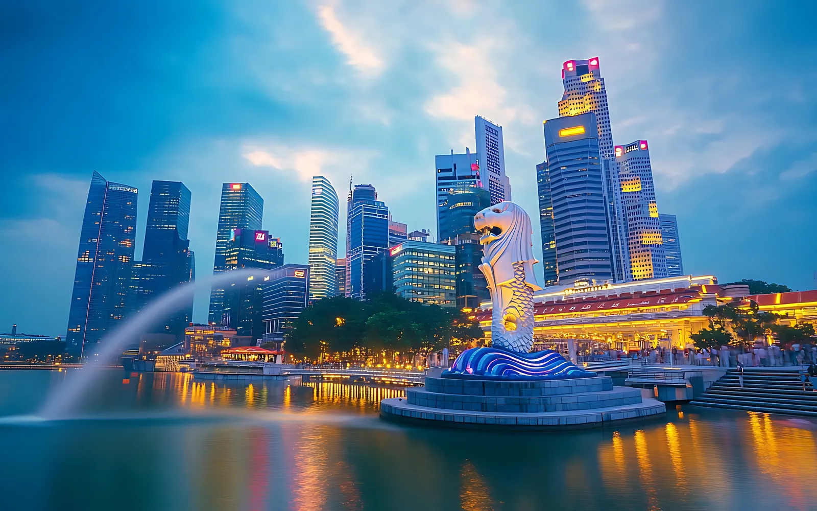 The Merlion statue spouting water in front of the lit Singapore skyline