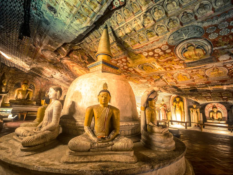 Golden Buddha statues and painted ceilings inside a cave temple