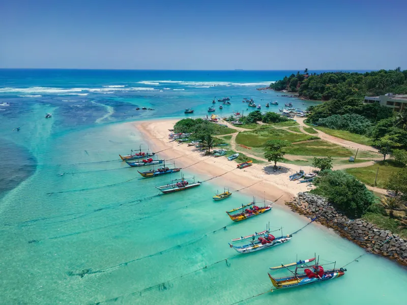 Fishing boats drawn up on a beach beside clear turquoise water
