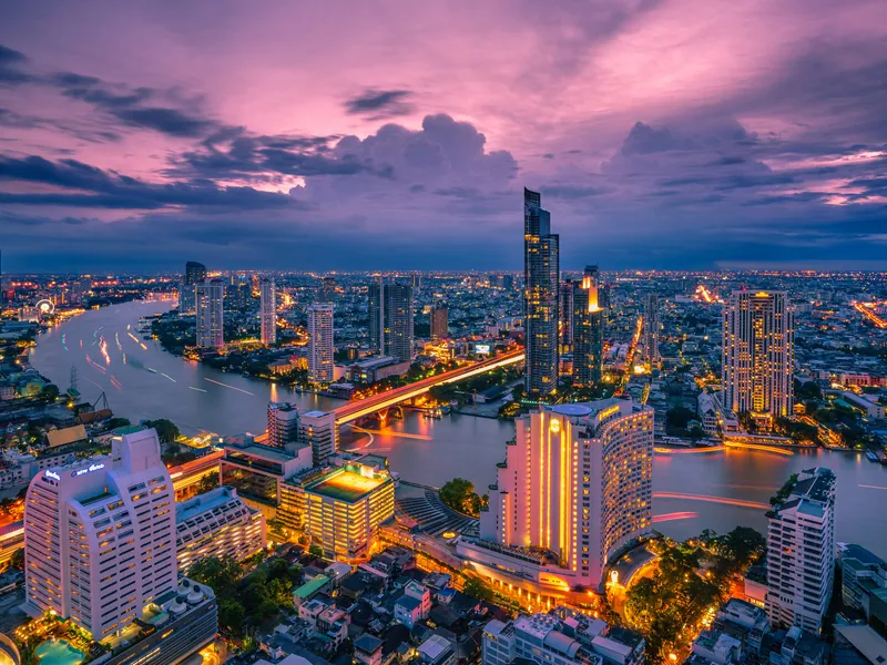 Bangkok at dusk, the river curving through the lit city