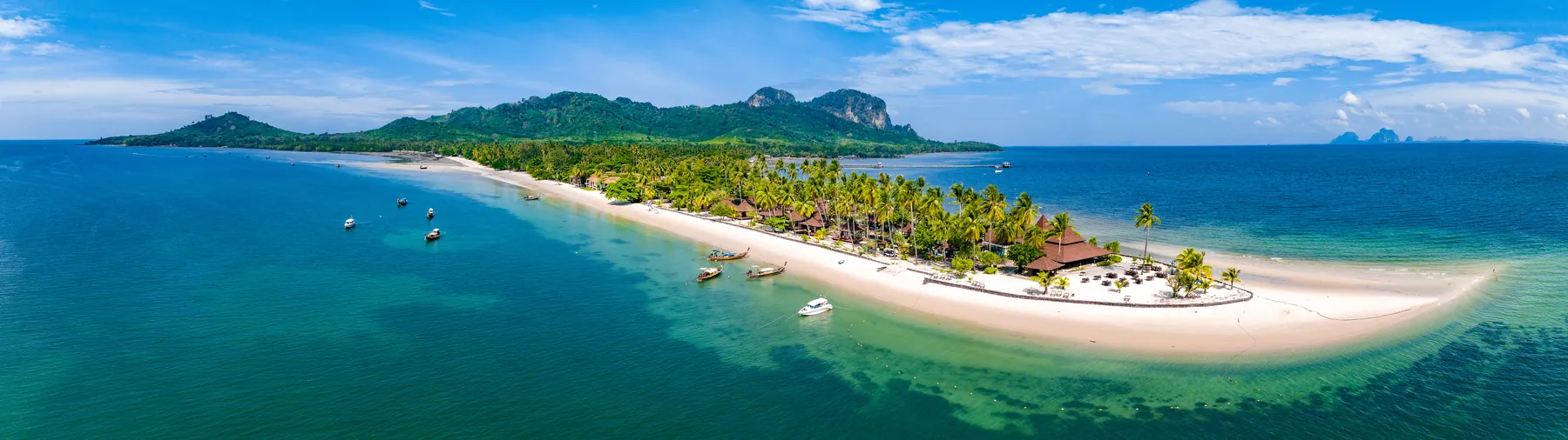 A long white sand spit fringed with palms running out into turquoise water in Krabi